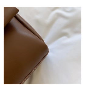 Détail du sac à main en cuir marron grainé avec des coutures contrastées blanches de qualité