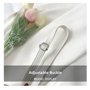 Detail of adjustable white leather shoulder strap with silver buckle on the stylish handbag