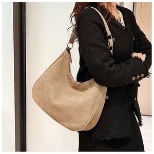 Detail view of khaki suede hobo bag with adjustable strap on black wool coat
