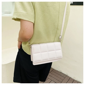Side view of a white quilted crossbody bag with adjustable silver buckle on a person