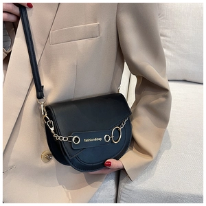 Close-up of black half-moon saddle bag with gold chain and fashion lettering