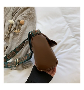 Détail de la besace en cuir marron avec une large bandoulière à imprimé ethnique