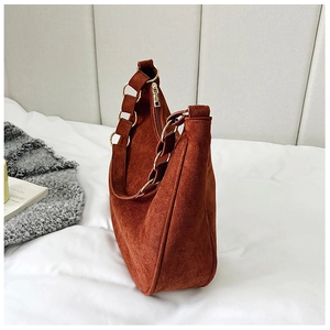 Close-up of brown suede hobo bag with crescent shape and gold metal ring hardware