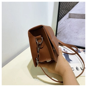 Close-up of brown leather crossbody bag featuring quilted stitching and accordion structure