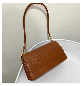 Close-up of crocodile pattern baguette bag with gold metal hardware on white chair