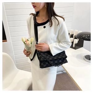 Detail of checkered shoulder bag with black chunky chain and woven fabric texture