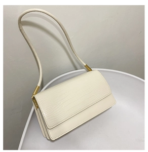 Close-up of crocodile-embossed cream leather texture and gold metal hardware detail