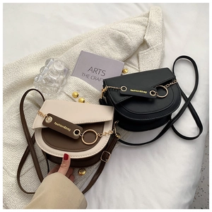 Detail of saddle crossbody bags with chain strap and metal ring decoration