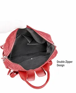 Detailed interior of red corduroy backpack showing storage pockets and dual zipper design