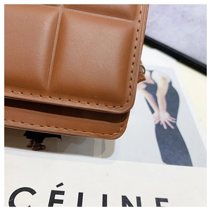 Detail of brown leather crossbody bag with quilted stitching on a fashion magazine