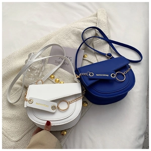 Detailed close-up of blue and white saddle bags with gold chain and fashion hangtag