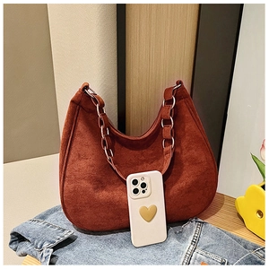 Detail of brick red suede underarm bag on denim jacket with a phone for size reference