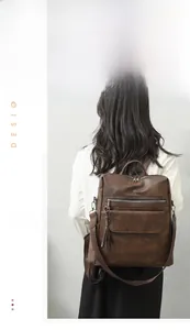 Detail of a brown vintage PU leather backpack with tassel charms and matte texture