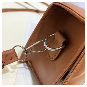 Close-up of silver lobster clasp and D-ring on brown leather crossbody bag strap