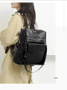 Detail view of the side profile on a black PU leather backpack with tassel and pockets