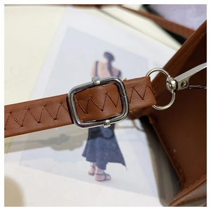 Detail of brown leather strap with silver square buckle and dark zigzag stitching
