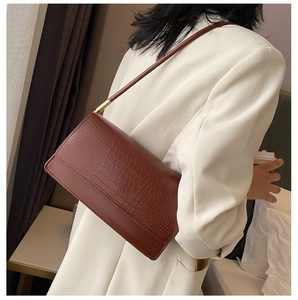 Brown crocodile pattern shoulder bag shown on a model wearing a white professional blazer