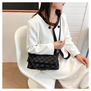 Detail of checkered crossbody bag with thick chain strap shown on a model