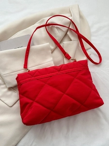 Détail d'un sac bandoulière matelassé rouge en nylon avec garniture dorée