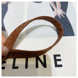 Detail of brown leather strap with decorative zig-zag stitching on a textured handbag