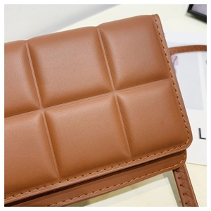 Macro detail of brown quilted crossbody bag showing fine stitching and leather texture