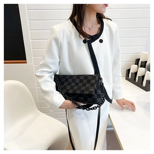 Detail of grey checkered crossbody bag showing fabric texture and black chain strap