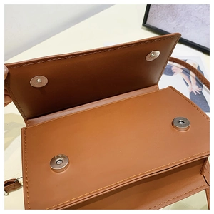 Close-up of caramel brown handbag showing magnetic snap closures and fine stitching details