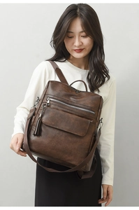 Detail of dark brown PU leather backpack with vintage fringe and metal zipper on model