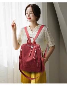 Detail of dark red corduroy backpack showing ribbed texture and vertical zipper pockets