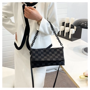 Detail of checkered shoulder bag with acrylic chain and pleated texture on the body