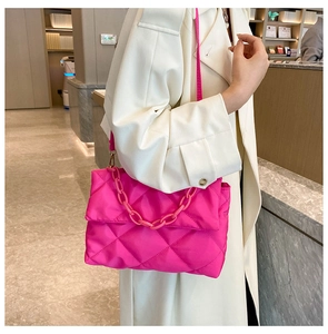 Gros plan du sac en nylon matelassé rose avec grande chaîne sur un manteau blanc