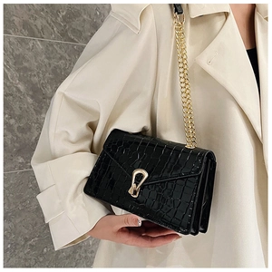 Detail of black faux crocodile skin shoulder bag with gold metal buckle and chain strap