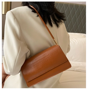 Deep brown crocodile pattern shoulder bag shown on a model in a minimalist setting