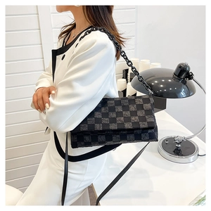 Detail of black checkerboard shoulder bag featuring bold chain strap and fabric texture