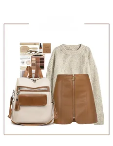 Flat lay of cream and caramel PU leather backpack with tassel, sweater and skirt