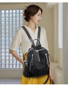 Detail of black corduroy backpack with silver zippers and rivets on a model