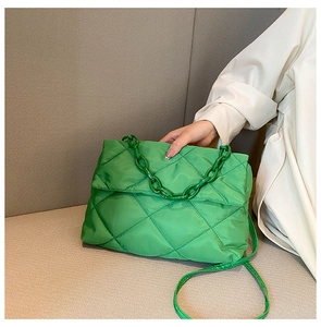 Détail d'un sac bandoulière matelassé vert vif avec une poignée à grosse chaîne