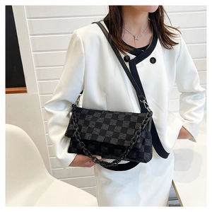 Detail of black checkerboard quilted fabric and chunky chain on the stylish crossbody bag