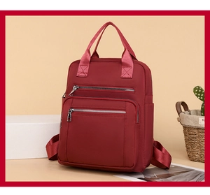Detail view of burgundy nylon backpack with dual front zippers and side water bottle pockets