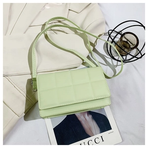 Detailed view of mint green quilted leather bag styled on a blazer with magazines