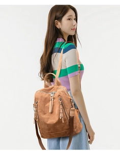 Brown corduroy backpack with dual metal zippers worn by model on white background