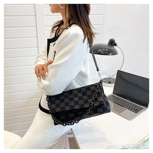 Modern black checkerboard pattern shoulder bag with chain detail in office setting