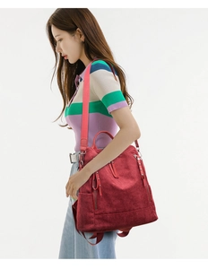 Detail of red corduroy backpack showing side pocket, tassels and detachable wide strap