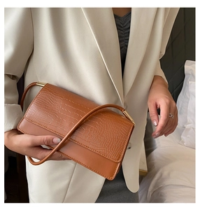 Brown crocodile embossed shoulder bag detail with gold buckle on a beige blazer