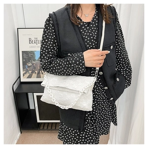 Detail of white quilted crossbody bag featuring resin chain and bubble texture finish