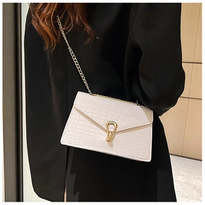Chic white crocodile pattern shoulder bag with gold horseshoe clasp on a black blazer