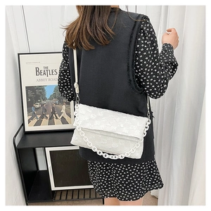 White quilted crossbody bag featuring a thick chain handle and adjustable shoulder strap