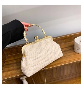 Detail of woven straw handbag with floral relief gold handle and classic ball clasp
