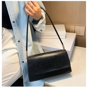 Close-up of black crocodile pattern baguette bag with minimalist gold hardware detail