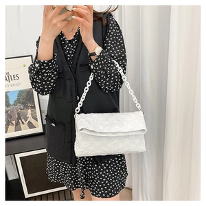Detail view of a white textured shoulder bag with a chunky chain strap and checkered pattern